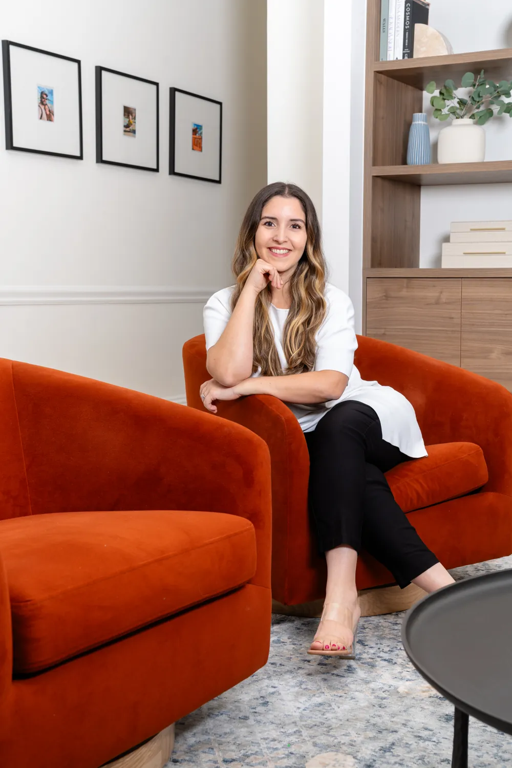 Camila Borges Chiang seated in a rust velvet chair in a home she designed