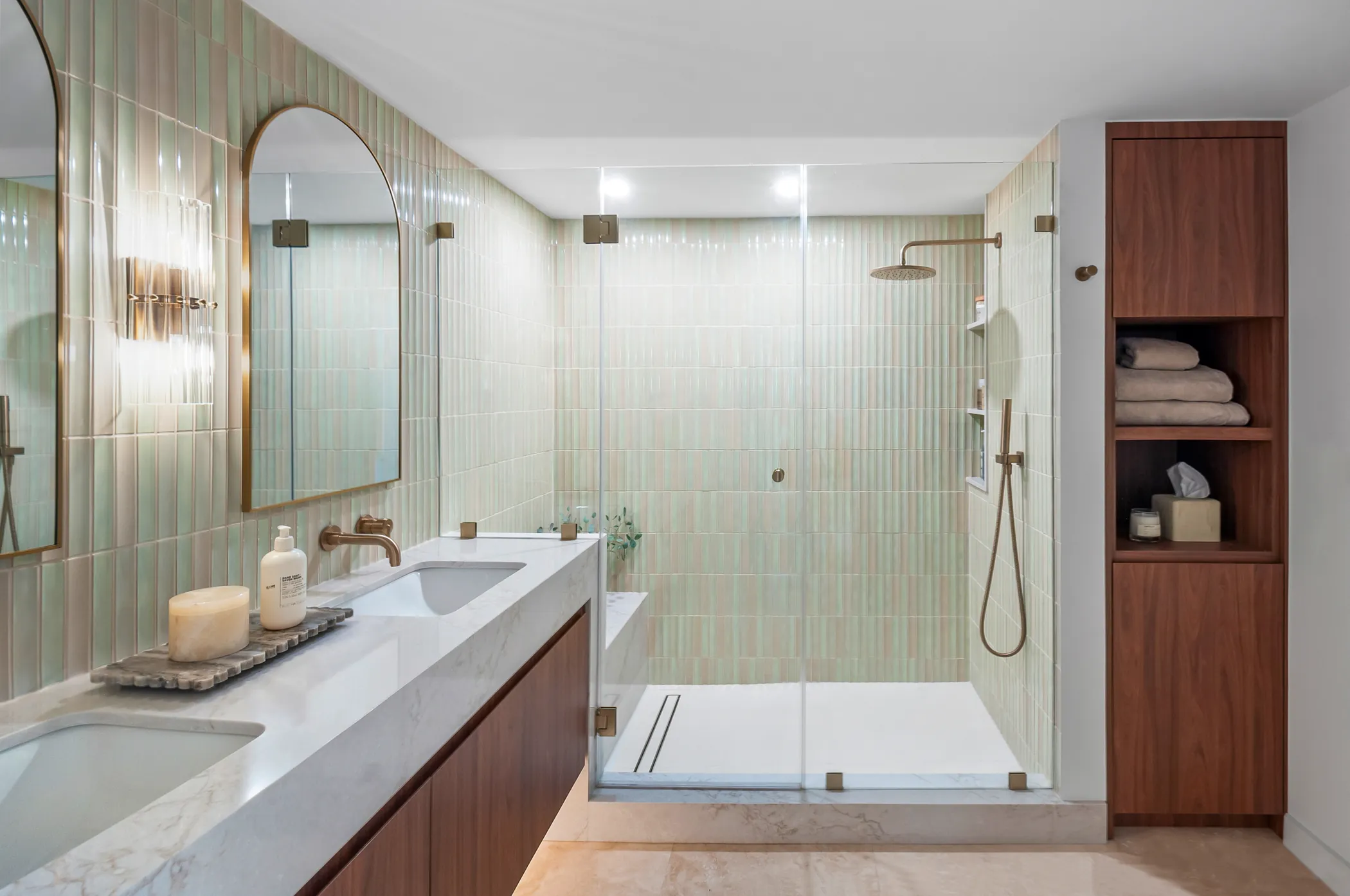 Primary bath with sage tile, walnut vanity, and arched mirrors