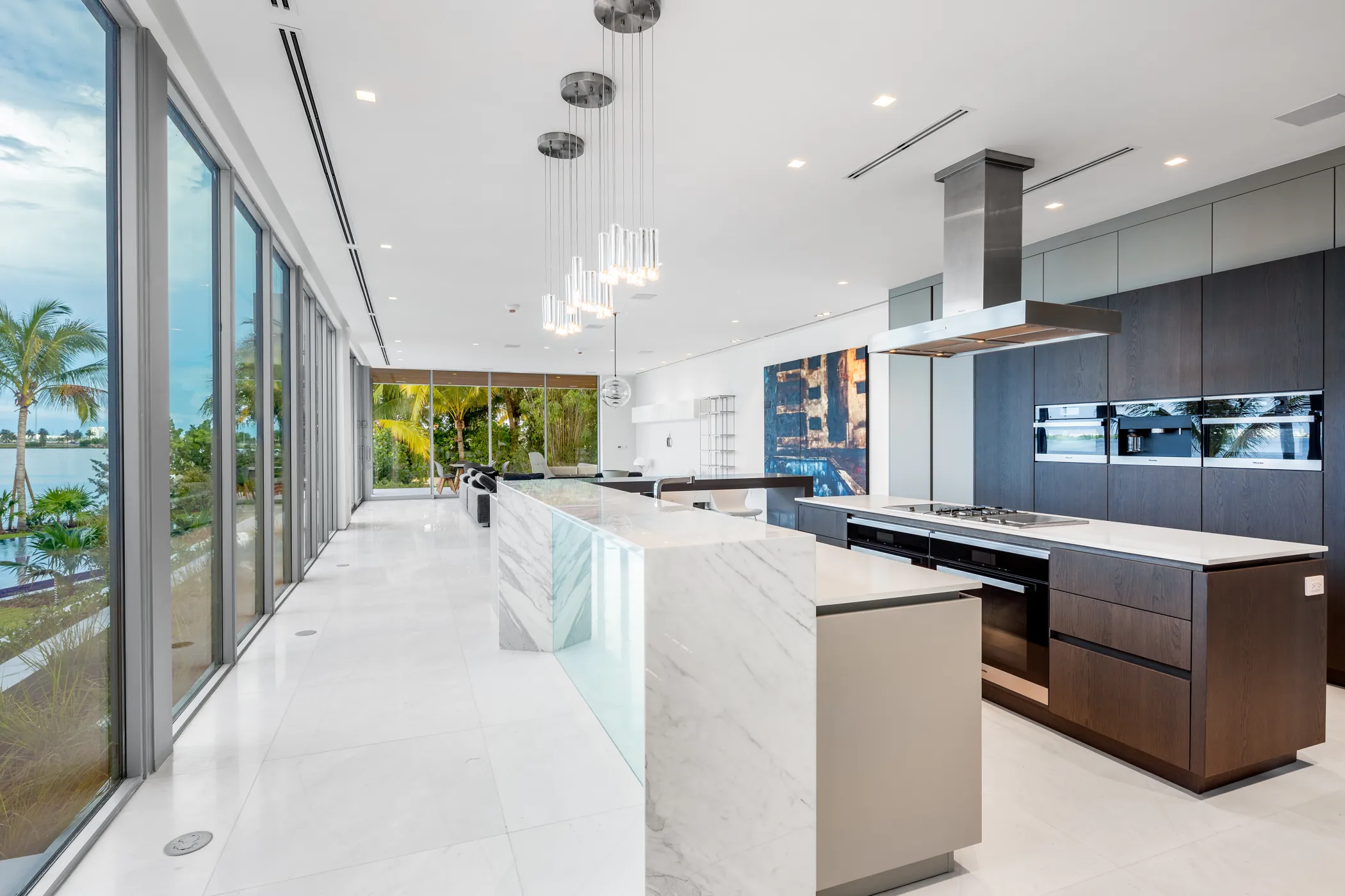 Long marble island in a glass-walled kitchen facing the water